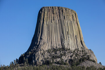 Image of national monument the Devils Tower in Wyoming against a bright blue sky.