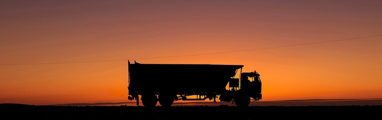 Fototapeta premium A semi trailer truck drives on a highway at sunset.