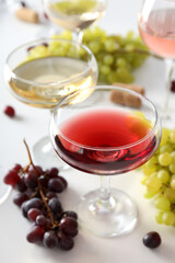 Wine in a glass with grapes on a light background.