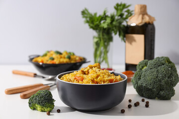 Pilaf in bowls, spices, vegetables and bottle on white background, close up