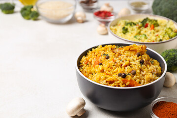 Pilaf, rice, spices in bowls and vegetables on light background, space for text