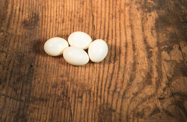 Peeled fresh organic eggs isolated on a rustic wooden table with advertising space.