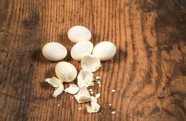 Peeled fresh organic eggs isolated on a rustic wooden table with advertising space.