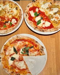 Three Italian thin crust pizzas on a restaurant table flat lay style