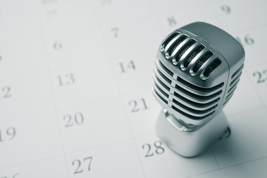 Classic retro microphone on white blank calendar background copy space. Concept of agenda, appointment or reminder in live podcast, meeting, concert, seminar, advertisement, learning, etc.