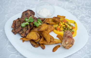 Barbecue with fried potatoes, sour cream and salad with peas and corn, Romania 2024