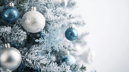 A beautifully decorated Christmas tree with silver and blue decorations, including snowflakes and icicles. The background is a solid icy white, creating a winter wonderland feel.
