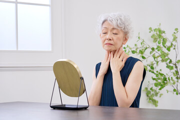 首のシワに悩む高齢者の女性