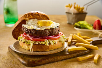 A close up of an egg beef burger sandwich with fries