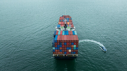 Fototapeta premium Aerial rear view Container Ship load container going to seaport or unload at container warehouse on the green sea. Logistics, import export, shipping or transportation Asia Pacific
