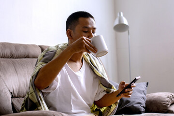 Young Asian Male Drinking Coffee After Waking Up From Sleep In The Morning