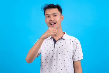 Young Asian Man Showing Eating in Sign Language Isolated on Blue Background.