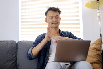 Young Asian Man Wear Causal Clothes Gesturing Sign Language on Video Call at Home
