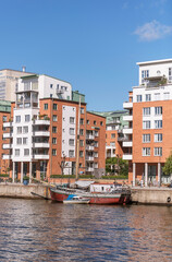 The harbor and piers with old fishing boat in the bay Hammarbysjö, apartment houses, a sunny summer day in Stockholm
