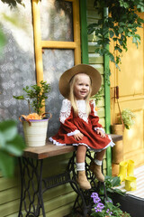 Beautiful little girl of two years old playing in the autumn yard. Little child playing in the yard of the house. Girl with long hair in a dress