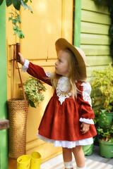 Beautiful little girl of two years old playing in the autumn yard. Little child playing in the yard of the house. Girl with long hair in a dress