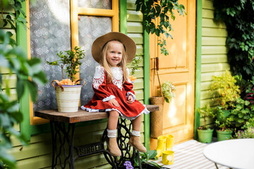 Beautiful little girl of two years old playing in the autumn yard. Little child playing in the yard of the house. Girl with long hair in a dress