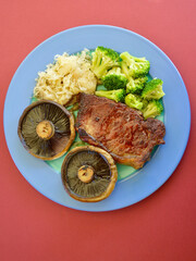 A porterhouse steak with mushrooms broccoli and sauerkraut.