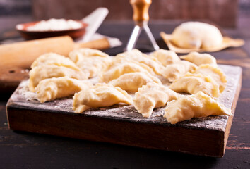 Raw Vareniks with potato filling on a wooden board / The concept is traditional Ukrainian cuisine. Horizontal orientation.