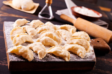 Raw Vareniks with potato filling on a wooden board / The concept is traditional Ukrainian cuisine. Horizontal orientation.