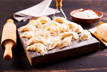 Raw Vareniks with potato filling on a wooden board / The concept is traditional Ukrainian cuisine. Horizontal orientation.
