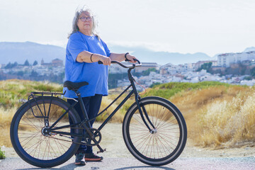Fototapeta premium overweight white-haired older woman riding a retro-style bicycle with a city in the background