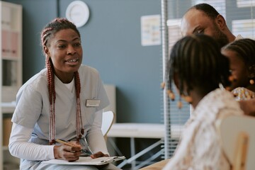 Nurse interacting with family members in medical office environment Engaging in conversation and writing notes, creating a professional and caring atmosphere in healthcare