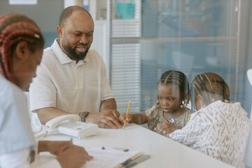 Obraz premium Counselor discussing important matters with parents and two children while seated around office desk. Advisor engaging with family in supportive environment