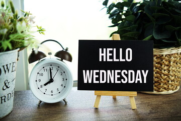Hello Wednesday text message with wooden easel and flower bouquet on wooden background
