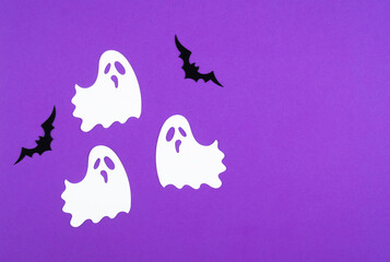 Playful ghosts and bats create a festive Halloween atmosphere on a vibrant purple background