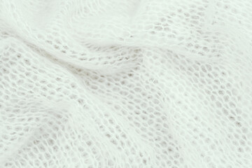 Soft white knitted fabric gently draped showcasing its texture and fine weave detail