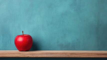 A vibrant red apple rests on a wooden shelf against a textured teal wall background.