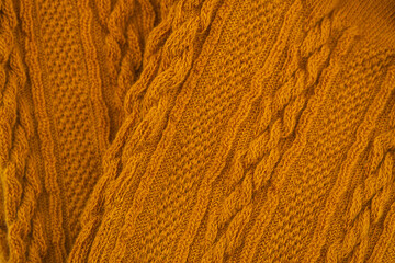 Textured mustard yellow knit fabric showcasing intricate patterns and interwoven designs