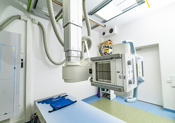 X-ray in a modern exam room. A high-tech x-ray machine hangs from the ceiling in a clinical examination room