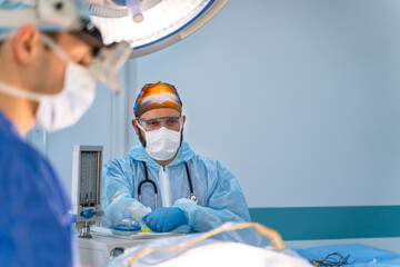 Surgeons operate in a sterile room. Surgical team in protective gear focuses on patient care while...