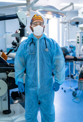 Surgeon readying for surgery. A healthcare worker clad in blue protective gear stands ready for surgery in a modern hospital environment, ensuring safety.