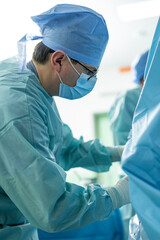 Surgeon operates in sterile setting. A surgical team is focused on an operation in a clean, sterile...