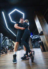 Couples dancing together in a modern gym setting. A couple enjoys a playful dance in a stylish gym, surrounded by workout equipment and neon lights