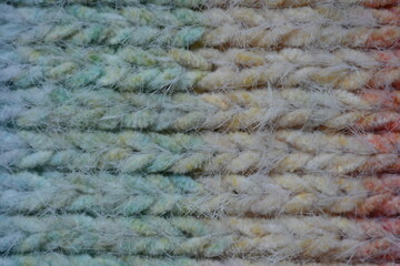 Macro texture of acrylic multicolored rainbow pastel crocheted winter clothing sweater as background, close-up of rainbow front surface, multicolored wool texture, crocheted front surface, part of sca