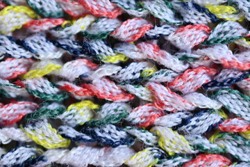 Macro texture of acrylic multicolored rainbow pastel crocheted winter clothing sweater as background, close-up of rainbow front surface, multicolored wool texture, crocheted front surface, part of sca