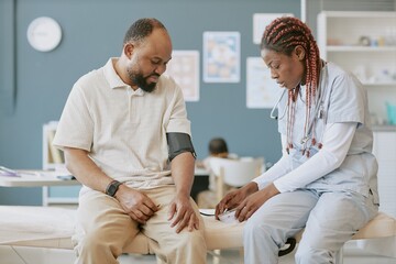 Obraz premium Medical professional in uniform with stethoscope examining patient seated in clinic setting providing care and attention against clinical backdrop