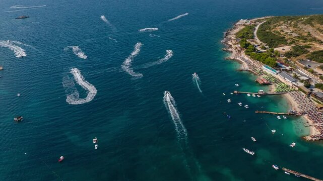Speedboats create trails across the turquoise waters of Ksamil during a bright summer day