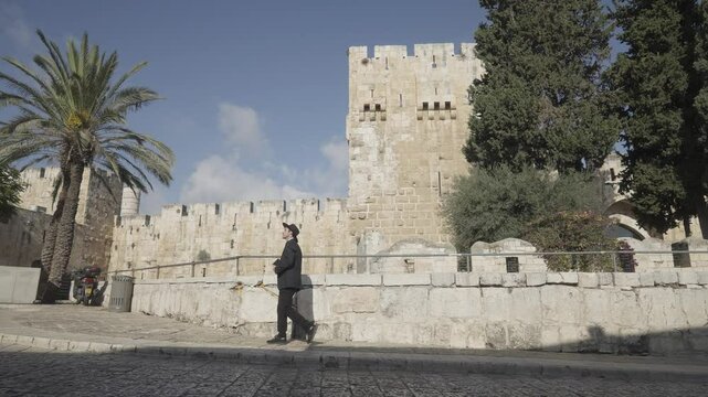 Orthodox Jew carrying a book walking in front of Tower of David in the Old City of Jerusalem, Israel