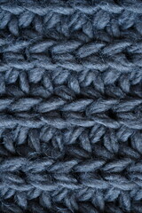 macro texture of woolen dark gray crocheted sweater as background, close-up of gray crocheted front surface, woolen texture of woolen wool, knitted front surface