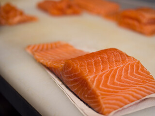 A stunning piece of salmon lies on a kitchen board, revealing its natural beauty and smooth texture. The salmon looks fresh and vibrant, perfect for creating a culinary masterpiece.
