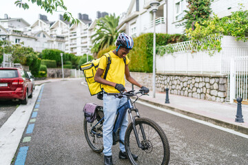 Obraz premium A man in a yellow shirt is riding a bicycle down a street