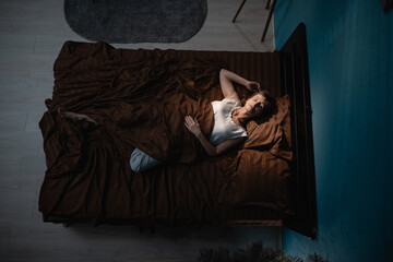Top view of apartment bedroom. Middle-aged woman sleeping comfortably on bed at night. Lady resting for productive day.