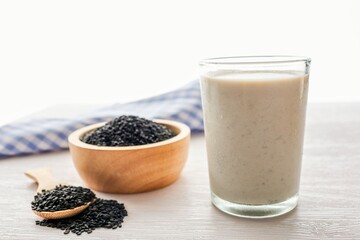 Black sesame with soymilk in the clear glass and black sesame in wooden bowl 