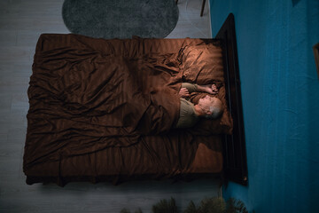 Top view of a senior elderly man sleeping comfortably on his bed in bedroom at night.