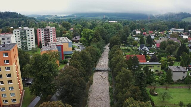 Drone shot of strong current river in the city under mountains